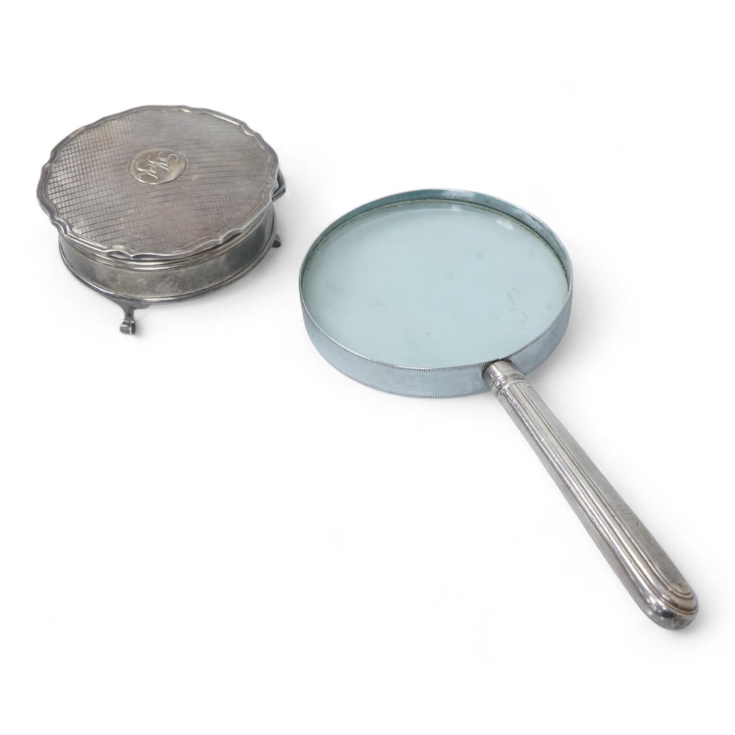 A George V silver mounted trinket box, by Adie Brothers, Birmingham, 1924, diameter 89mm. and a chrome magnifying glass, later added to a knife handle, handle by Goldsmiths & Silversmiths Co Ltd, London, 1894, 21.7cm.